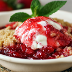 Freshly baked strawberry cobbler in a rustic dish, featuring a golden brown crumble topping and garnished with mint leaves.