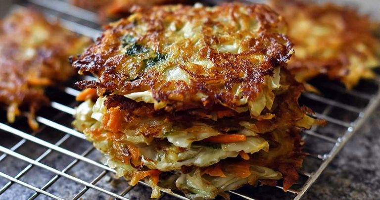 Crispy cabbage fritters served on a plate with herbs and a dipping sauce.