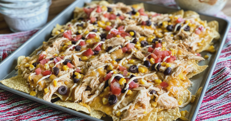 Close-up of creamy slow cooker chicken nachos garnished with cilantro on a wooden table.