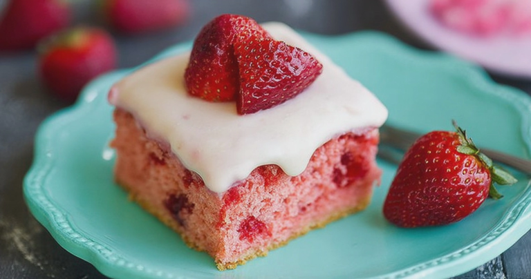 Sliced healthy strawberry cake on a wooden table, garnished with fresh strawberries.