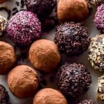 Homemade chocolate truffles coated in cocoa powder on a wooden surface with chocolate shavings