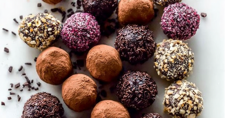 Homemade chocolate truffles coated in cocoa powder on a wooden surface with chocolate shavings