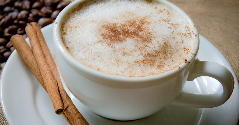 Stylish homemade cappuccino topped with cocoa powder on a wooden table.