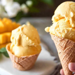 Homemade mango ice cream in a bowl garnished with mango slices and fresh mint leaves.
