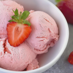 Creamy keto strawberry ice cream in a bowl with fresh strawberries and mint, perfect for a low-carb dessert.