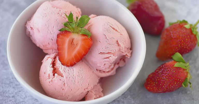 Creamy keto strawberry ice cream in a bowl with fresh strawberries and mint, perfect for a low-carb dessert.