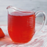 Homemade sugar-free strawberry syrup in a glass jar with fresh strawberries and mint leaves.
