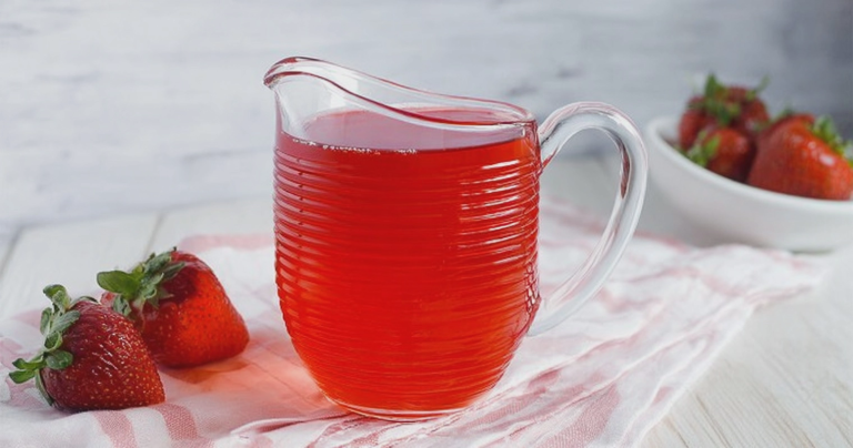 Homemade sugar-free strawberry syrup in a glass jar with fresh strawberries and mint leaves.