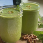 Flat belly smoothie in a glass with mint leaves and lime slice, surrounded by fresh ingredients.