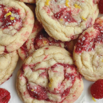 Plate of freshly baked lemon raspberry cookies with a light golden color and pieces of raspberries visible.