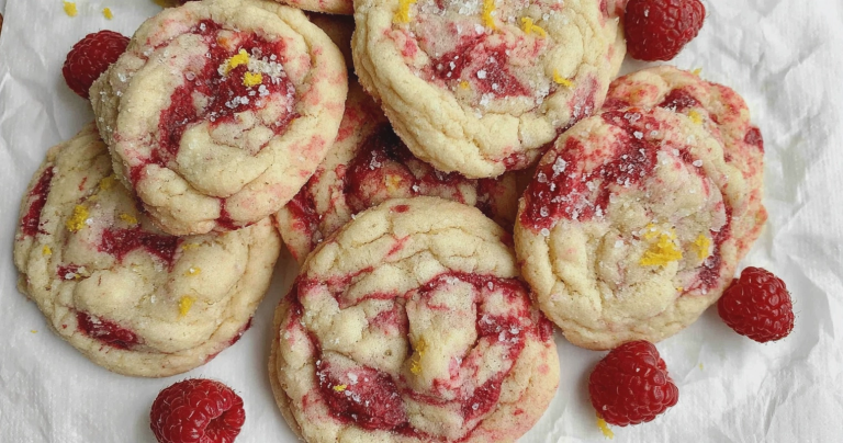 Plate of freshly baked lemon raspberry cookies with a light golden color and pieces of raspberries visible.