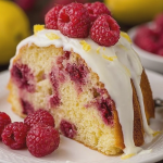 Lemon Raspberry Bundt Cake topped with raspberries and lemon slices on a wooden table.