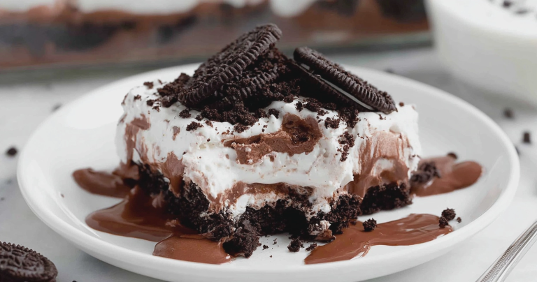 Slice of no bake chocolate lasagna on a wooden table, highlighting layers of Oreo crust, cream cheese filling, chocolate pudding, and chocolate chips.