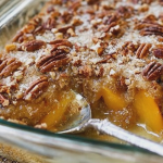 Warm peach dump cake topped with whipped cream and surrounded by fresh peaches.