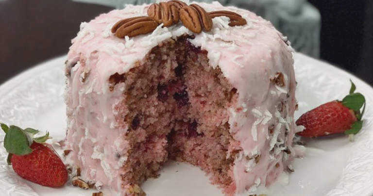 Slice of strawberry pecan cake showing layers of strawberries and pecans, surrounded by fresh strawberries and nuts.